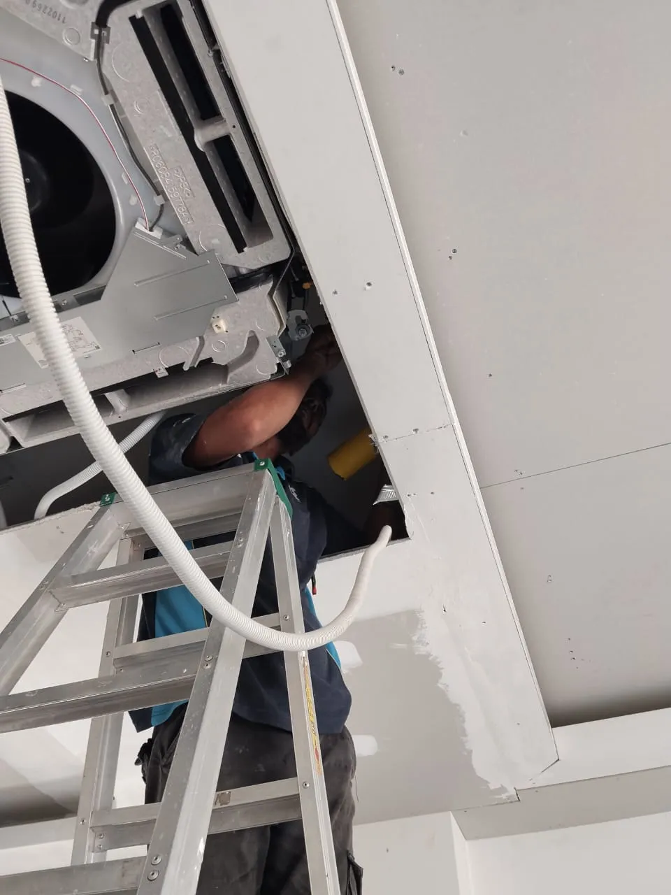 Aircond service technician working on an air conditioning unit in Batu Caves, KL & Selangor