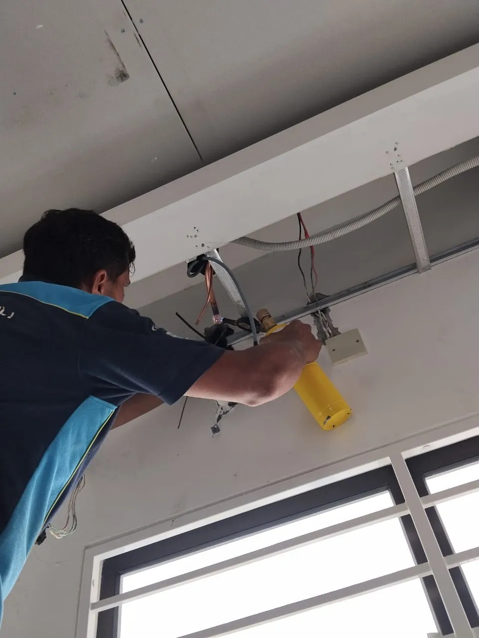 KL Renovator technician performing PCB control-board diagnosis and repair on an aircond unit in aircond chemical wash